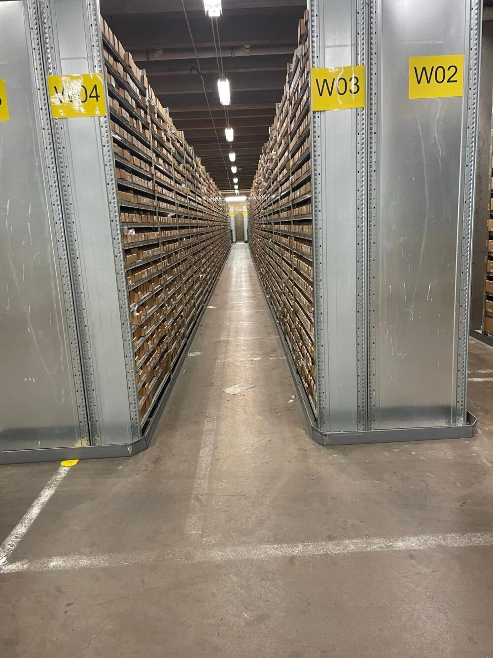 En tom golvyta i en lagerlokal med hyllställ på vardera sida.